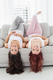 Cheerful brunette and redhead lying on sofa in living room