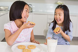 Girls enjoying cookies and milk in kitchen