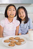 Two girls enjoying cookies and milk in kitchen