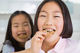 Little girl feeding her elder sister a cookies in kitchen