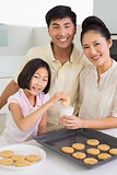 Girl enjoying cookies and milk with parents in kitchen