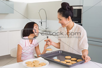 Girl looking at her mother prepare cookies in kitchen