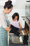 Girl helping her mother prepare cookies in kitchen