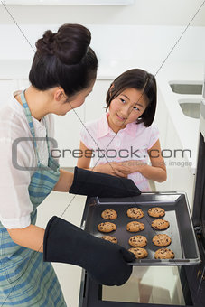 Girl helping her mother prepare cookies in kitchen