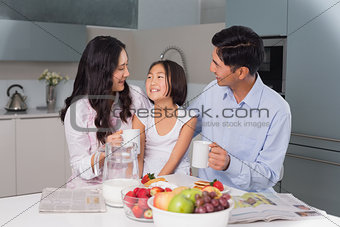 Happy young girl enjoying breakfast with parents