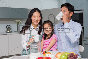Portrait of a happy young girl enjoying breakfast with parents