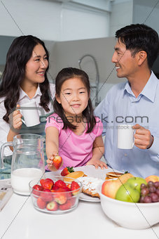 Portrait of a young girl enjoying breakfast with parents