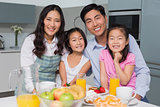 Cheerful family of four enjoying healthy breakfast in kitchen