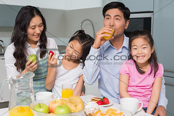 Cheerful family of four enjoying healthy breakfast in kitchen