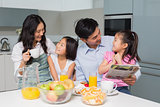 Family of four enjoying healthy breakfast in kitchen