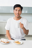 Smiling young man drinking coffee in kitchen
