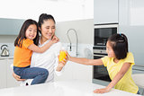 Girl offering her mother a glass of orange juice in kitchen