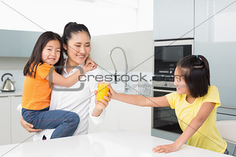 Girl offering her mother a glass of orange juice in kitchen