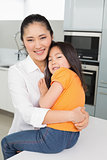 Portrait of a mother carrying her young daughter in kitchen