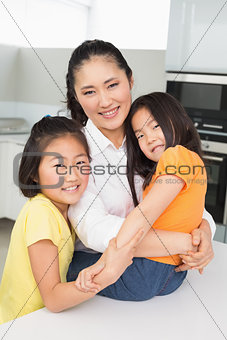 Smiling mother with her young daughters in kitchen