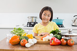 Cute young girl with raw vegetables at the kitchen counter