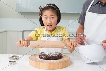 Shocked girl with her father preparing cookies in kitchen