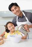 Man with his daughter using electric whisk into bowl in kitchen