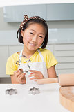 Smiling young girl holding cookie mold in kitchen