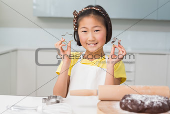 Smiling young girl holding cookie molds in kitchen