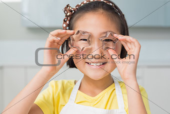 Close-up portrait of a smiling young girl holding cookie molds