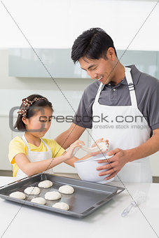 Man with his daughter preparing cookies in kitchen