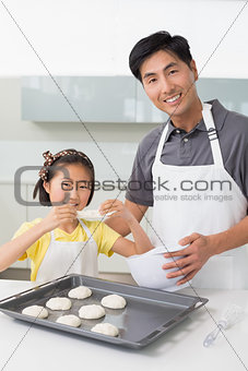 Man with his daughter preparing cookies in kitchen
