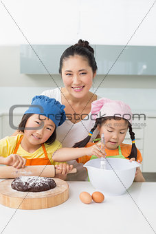 Girls with their mother preparing cookies in kitchen