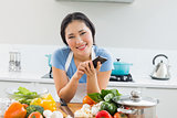 Smiling woman text messaging in front of vegetables in kitchen