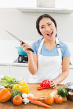 Thoughtful smiling woman chopping vegetables in kitchen