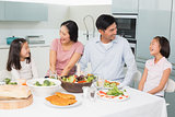 Cheerful family of four enjoying healthy meal in kitchen