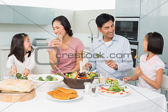 Young family of four enjoying healthy meal in kitchen