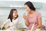 Little girl and mother eat food in kitchen