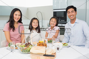Happy family of four enjoying healthy meal in kitchen