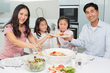 Happy family of four enjoying spaghetti lunch in he kitchen