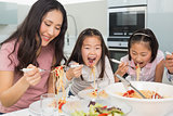 Woman with kids enjoying spaghetti lunch in kitchen