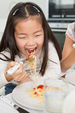 Happy young kid enjoying spaghetti lunch in kitchen