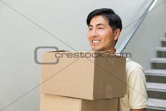 Smiling young man carrying boxes