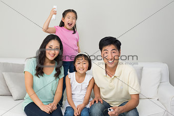 Happy family of four watching tv in living room