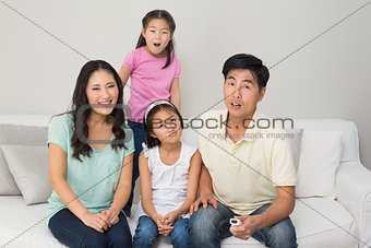 Portrait of a family of four watching tv in living room