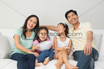 Happy family of four watching tv in living room
