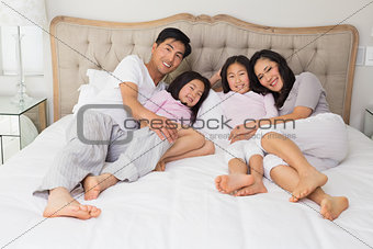 Full length of a happy family of four lying in bed