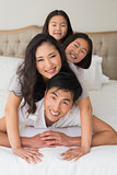 Cheerful family of four lying over each other in bed