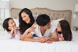 Cheerful family of four lying in bed