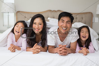 Portrait of a cheerful family of four lying in bed