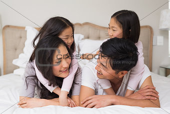Loving family of four lying in bed at home