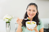 Smiling young woman with a bowl of salad in kitchen