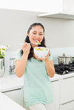 Smiling young woman with a bowl of salad in kitchen