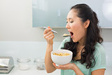 Young woman eating cereals in kitchen