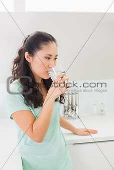 Young woman drinking water in kitchen